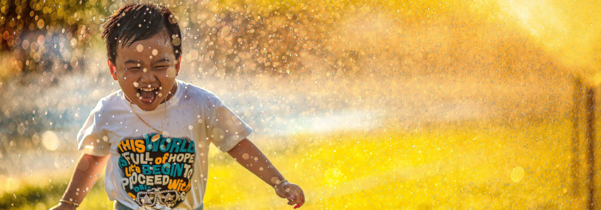 Child running through sprinklers