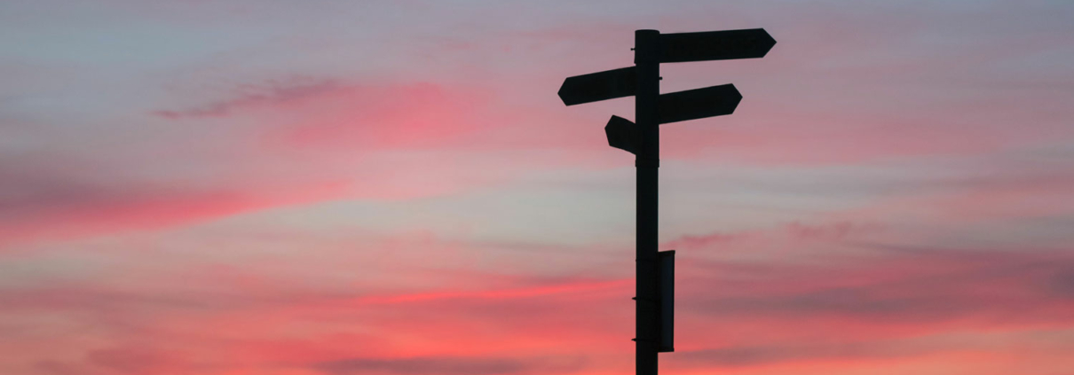 signpost in front of sunset