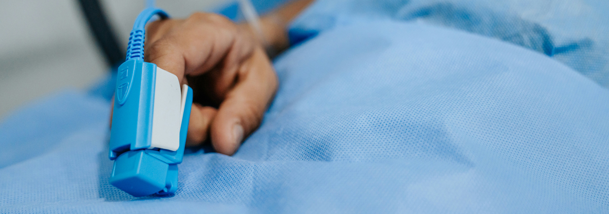 hand in a hospital bed with a blood pressure monitor