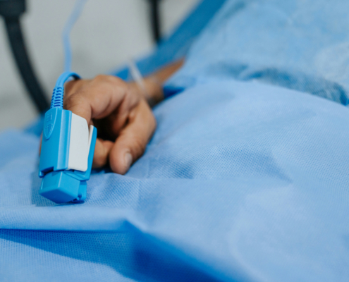 hand in a hospital bed with a blood pressure monitor