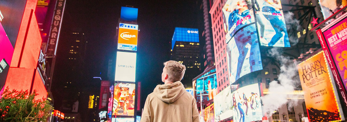 man stares up at advertising billboards