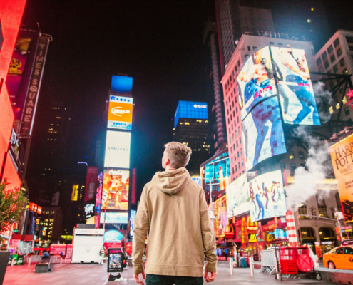 man stares up at advertising billboards
