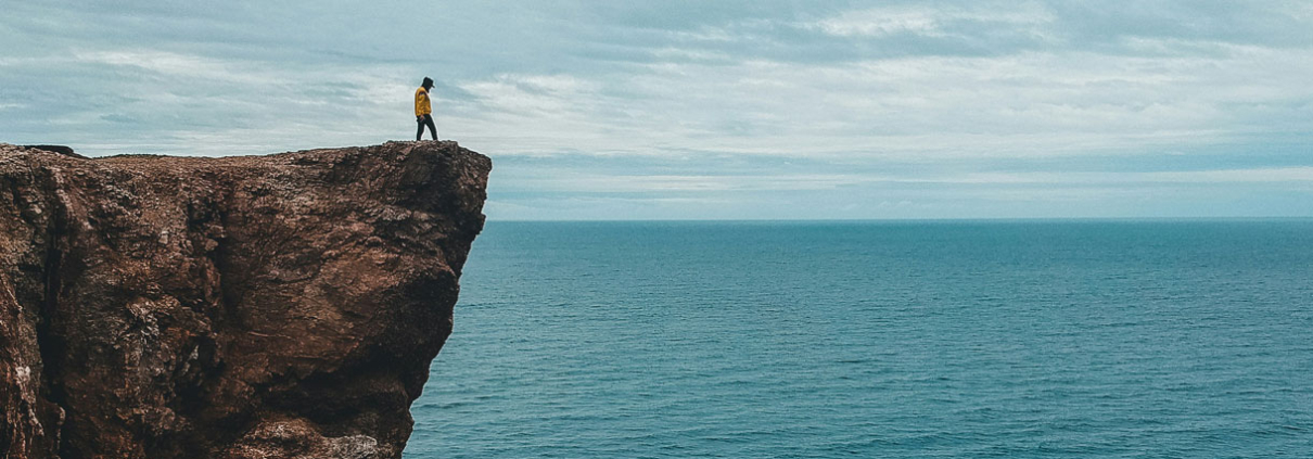 man staring over edge of cliff