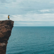 cliff man staring over edge of cliff