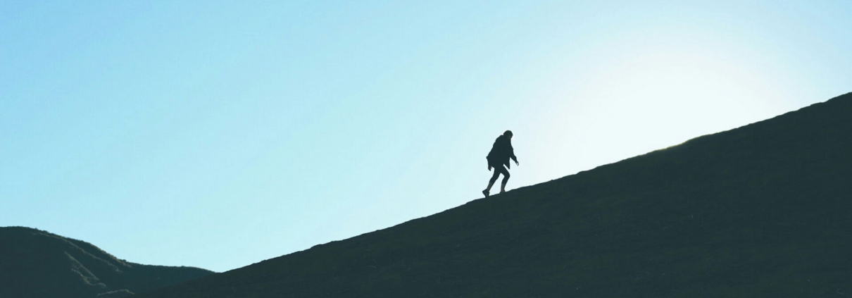 man silhouetted climbing a mountain