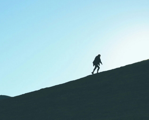 man silhouetted climbing a mountain